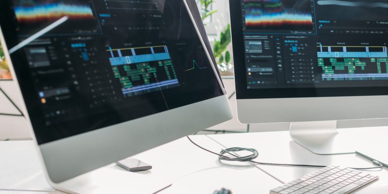 selective focus of computer monitors near headphones and plant on table